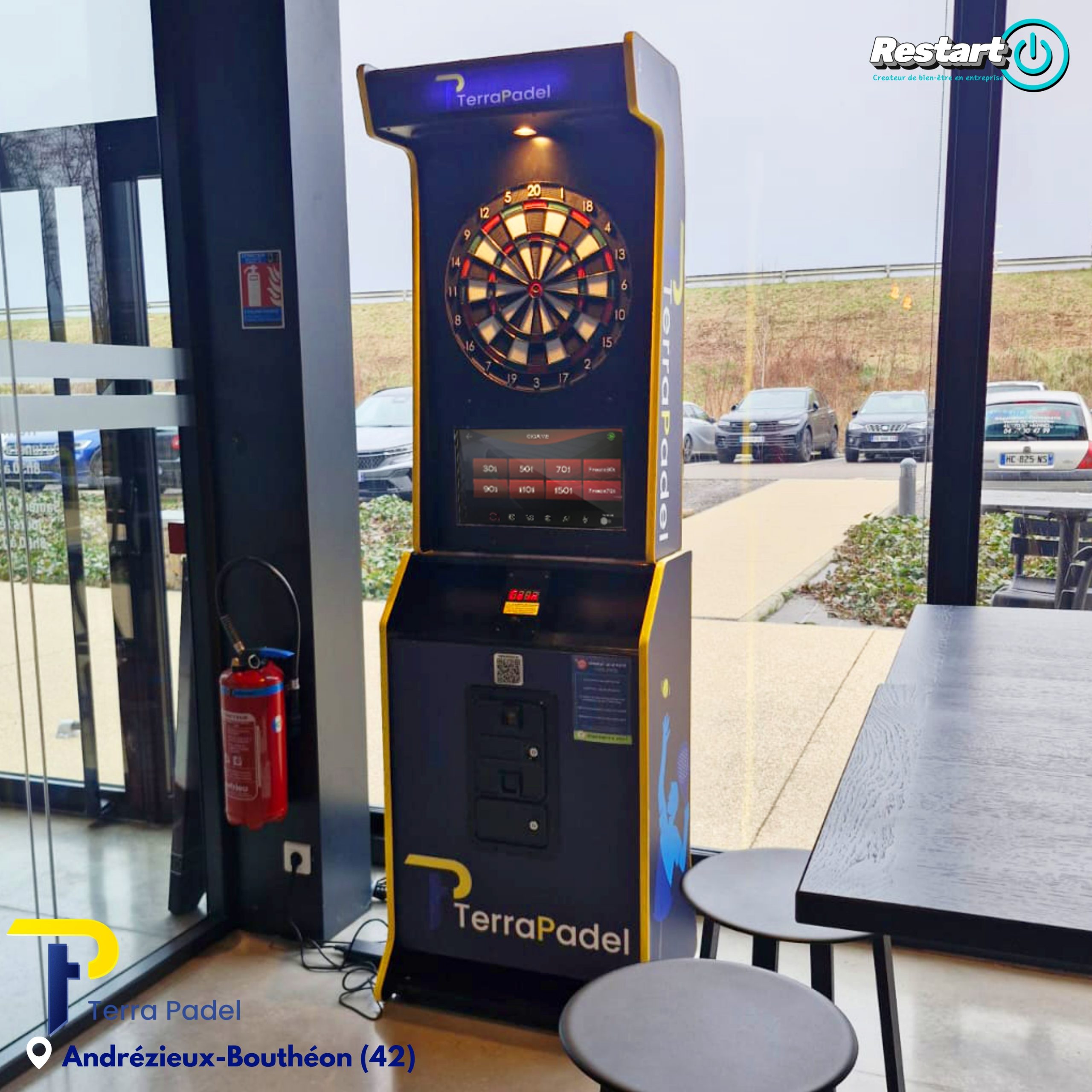 Borne de fléchettes interactive TerraPadel installée à Andrézieux-Bouthéon, à côté d’une table haute dans l’espace détente