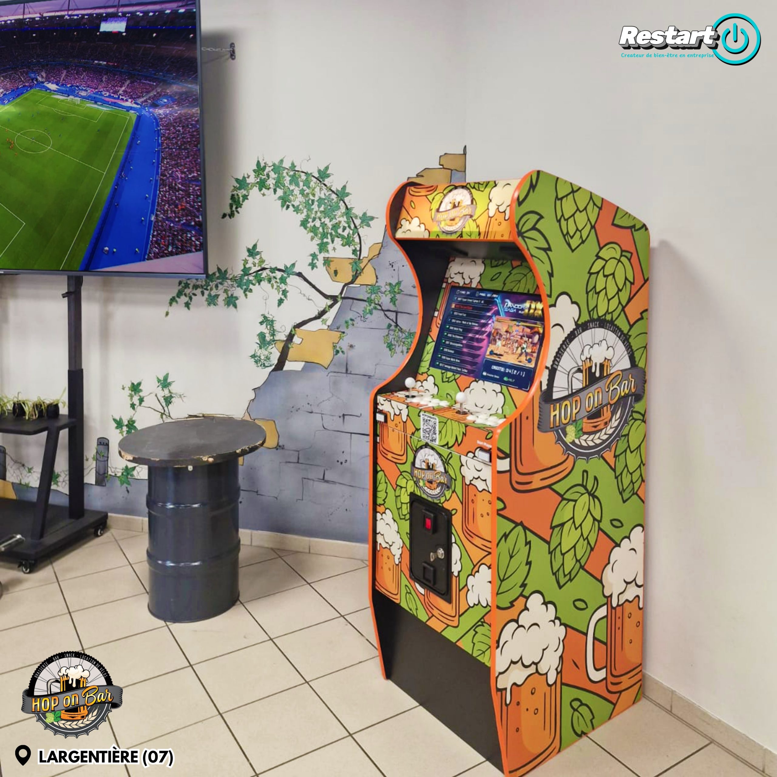 Borne d’arcade personnalisée Hop On Bar installée à Largentière près d’un écran diffusant un match de football