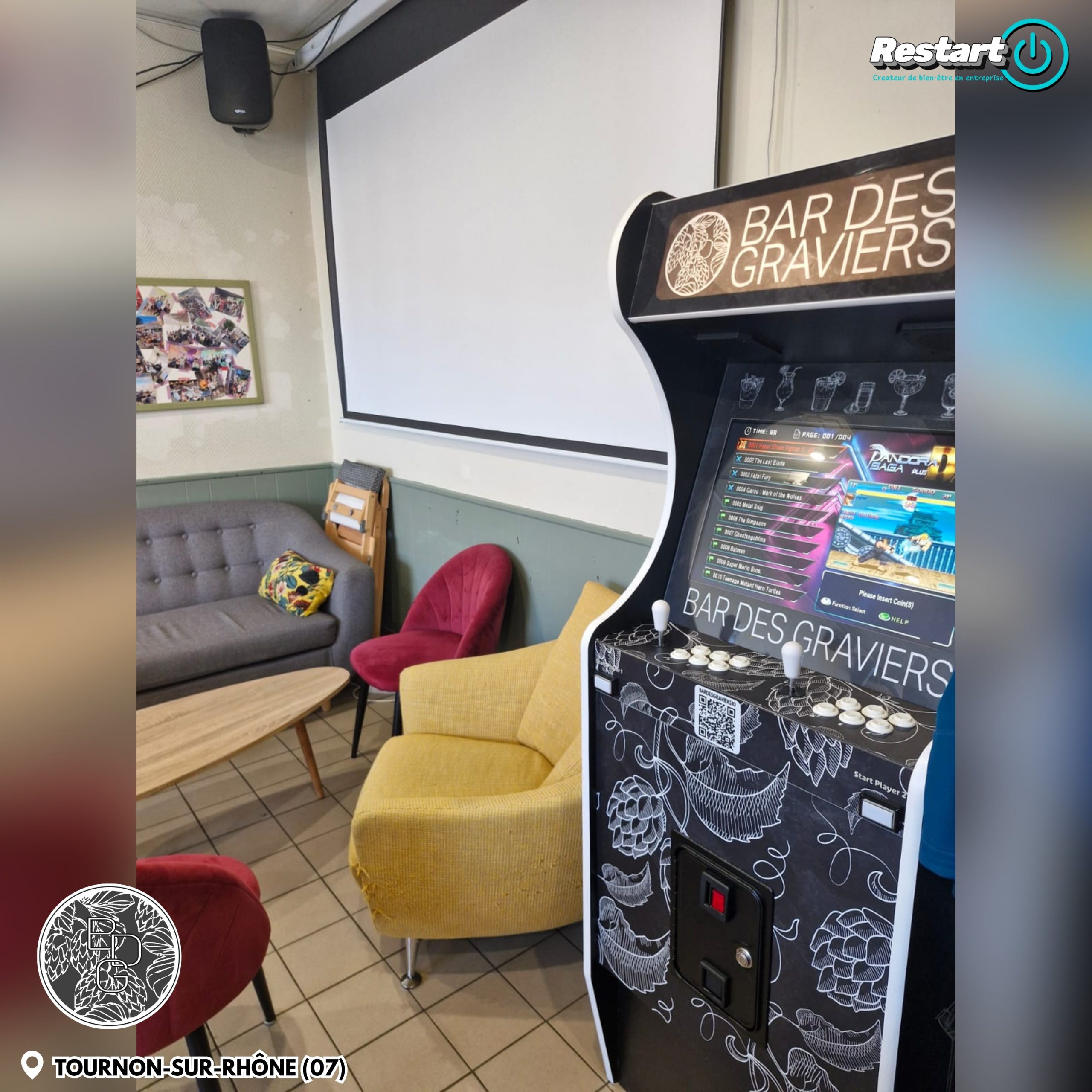 Borne d’arcade noire et blanche personnalisée pour le Bar des Graviers, installée dans un espace détente avec des fauteuils