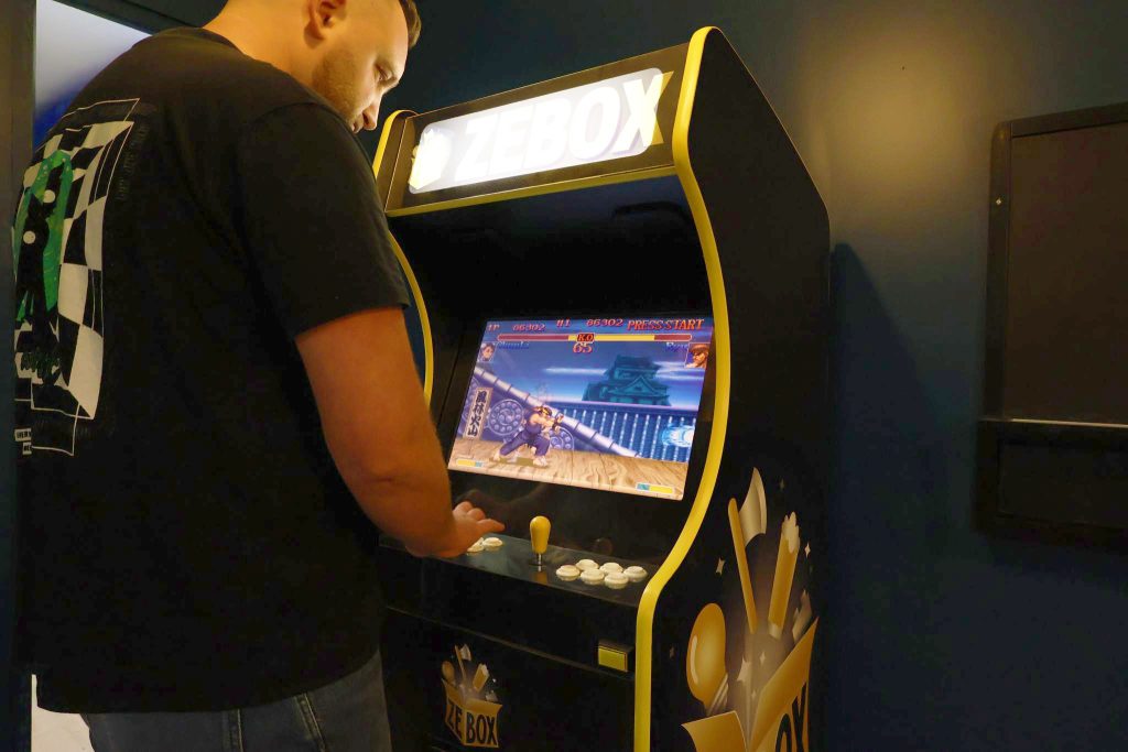 Joueur utilisant une borne d’arcade personnalisée ZEBOX dans un espace de divertissement