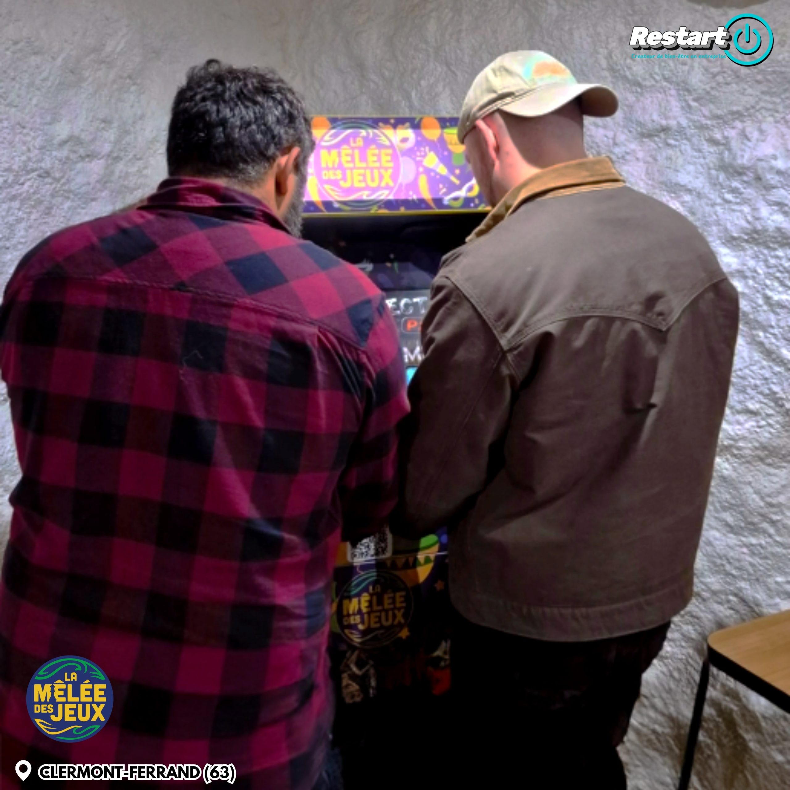 Deux joueurs de dos utilisent une borne d’arcade personnalisée La Mêlée des Jeux à Clermont-Ferrand