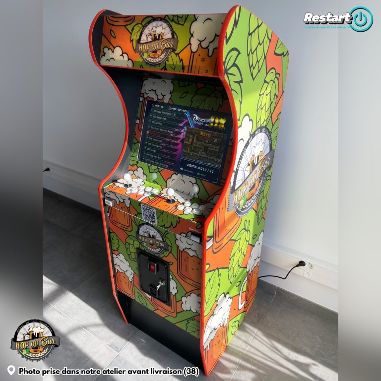 Borne d’arcade personnalisée Hop On Bar aux couleurs orange et vert, avec motifs de bière et de houblon, photographiée dans l’atelier avant livraison