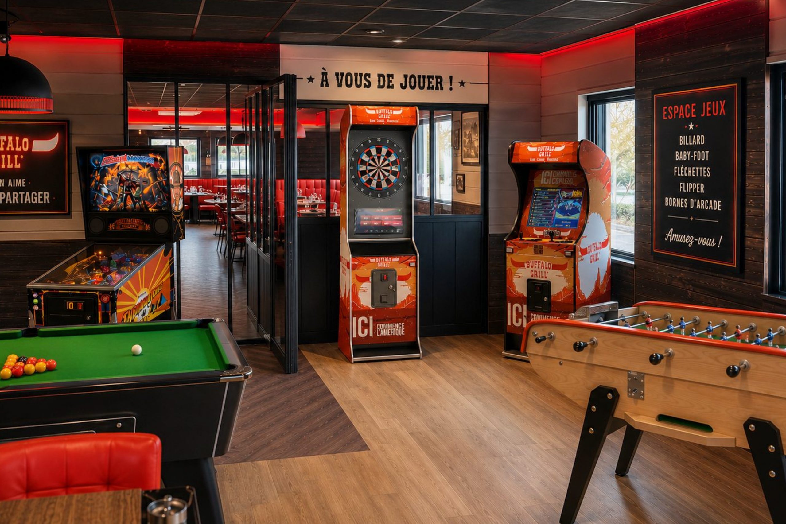 Vue d’ensemble d’un espace jeux Buffalo Grill avec borne d’arcade, fléchettes interactives, flipper, billard et baby-foot