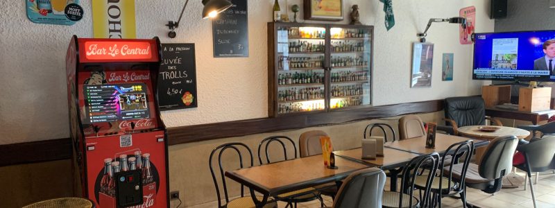 Borne d’arcade personnalisée rouge et noire installée dans la salle du Bar Le Central